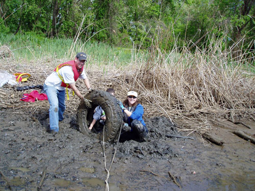 MDE's Renee Godinez and a volunteer remove a tire from the Anacostia River.